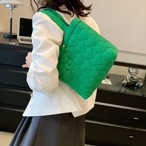 Green quilted tote bag with heart pattern shown on model in a modern home setting