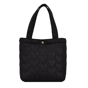 Minimalist black tote bag with heart-quilted pattern and gold snap button closure