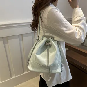 Sac seau bleu clair à cordon avec papillon argenté et chaîne perlée porté par un mannequin