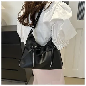 Dettaglio della borsa tote nera con fiocchi decorativi e cerniere sulla spalla