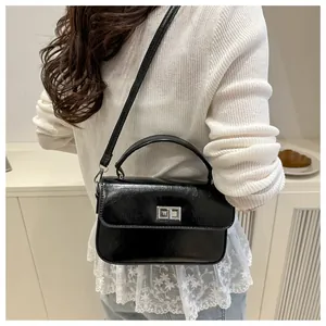 Detail of black glossy crossbody bag with silver twist lock and smooth leather finish
