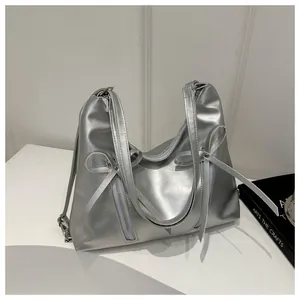 Close-up of silver metallic shoulder bag with bow details and vertical zippers