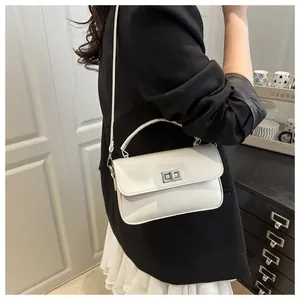 Detail of white rectangular crossbody bag with silver rotating lock and fine texture