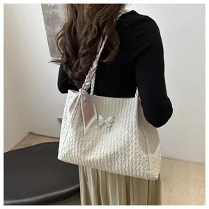 Detail of off-white tote bag with wave texture, silver butterfly charm and silk scarf handle