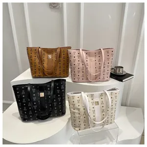 Lot de quatre sacs cabas imprimés en marron rose noir et blanc exposés sur un podium