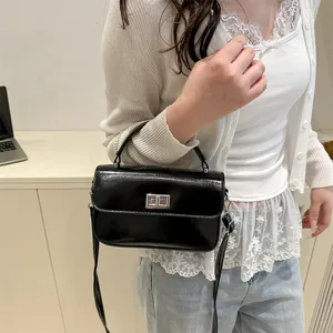 Glossy black leather crossbody handbag for women with silver buckle and top handle