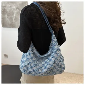 Detail showing blue checkered denim texture and distressed fringe edges on the hobo bag