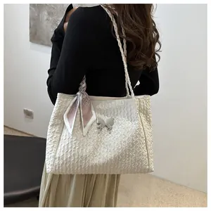 Detailed view of white pleated tote bag featuring a silver metal butterfly and pink silk scarf