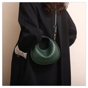 Gros plan du sac demi-lune tressé vert foncé avec boucles dorées et bandoulière