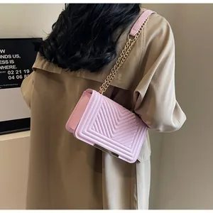 Detail of pink quilted square bag with gold metal clasp and chain strap on a coat