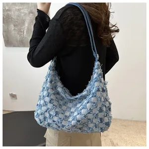 Detail of blue and white checkered denim hobo bag featuring frayed tassel edges and texture
