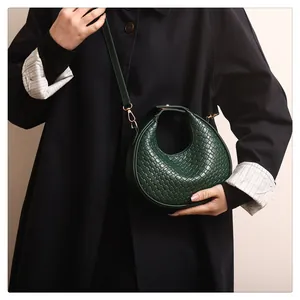 Détail du sac hobo demi-lune vert foncé tissé avec ferrures dorées et bandoulière élégante