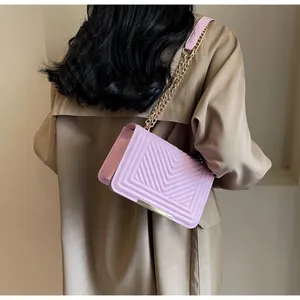 Detail view of pink quilted crossbody bag with gold chain strap worn over a khaki coat