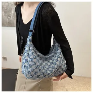 Detail of blue denim hobo bag with frayed checkerboard texture and adjustable strap