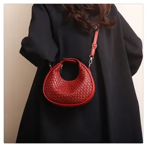 Détail du sac demi-lune rouge tressé avec boucle en métal doré et bandoulière réglable