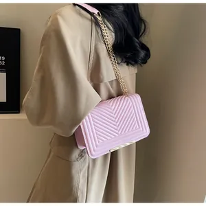 Pink chevron quilted crossbody bag with gold chain strap shown on khaki trench coat