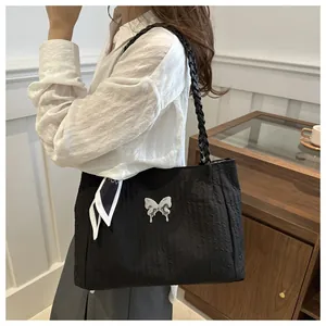 Detail of black tote bag with textured nylon, silver butterfly, and silk scarf accents