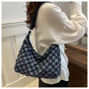Detail of dark blue denim tote bag with light blue checkerboard pattern and frayed edges