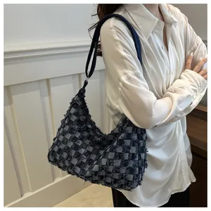 Detail of denim checkerboard hobo bag with fringe texture on a female model side view