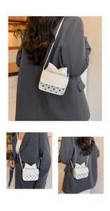 Detailansicht einer weißen Mini-Umhängetasche mit Schleife, Punkten und Modeprägung