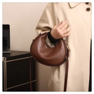 Détail du sac demi-lune tressé marron foncé avec bandoulière et boucle dorée