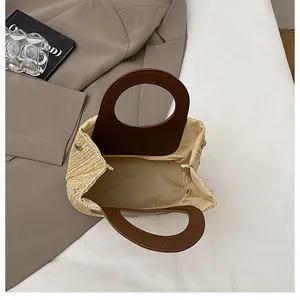 Detail of hand-woven straw bag showing round leather handles and fabric lining interior