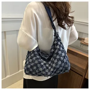 Detail of blue and white checkered hobo bag with frayed edges worn by a model