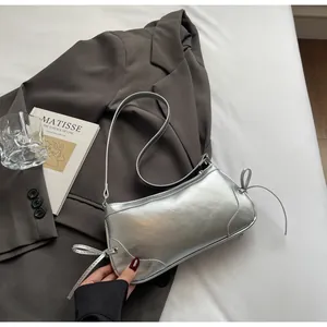 Detail of silver metallic shoulder bag with side bow ribbons on a gray suit jacket