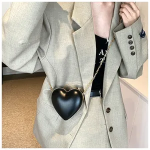 Détail d'un sac à bandoulière chic noir en forme de cœur avec cadre doré et chaîne