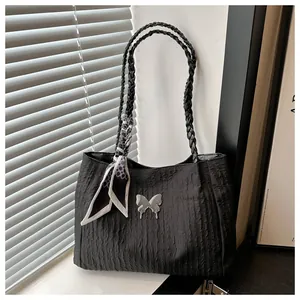 Detail of black pleated tote bag with silver butterfly accent and woven handle decoration