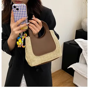 Detailed view of handmade woven straw bag with beige herringbone texture and brown leather handle