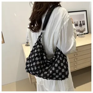 Detail of black and white checkered tweed tote bag with fringe edge on model shoulder