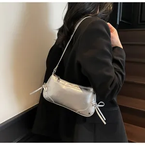 Silver matte baguette bag with bow drawstrings worn with a black suit for casual style