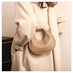 Vue détaillée de la texture du sac croissant tissé et de la bandoulière sur le manteau