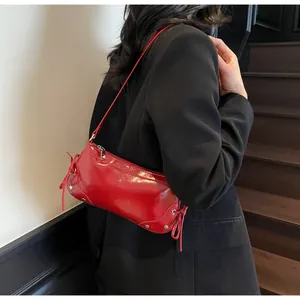 Detail view of red patent leather shoulder bag with silver studs and side bow knots