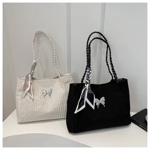 Detail of woven handles on large tote bags with metal butterfly and silk scarf accents