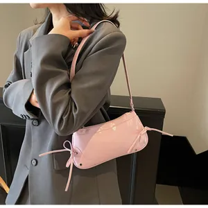 Light pink patent leather shoulder bag with bow and rivet details on model