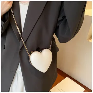 Gros plan d'un sac à main blanc en forme de cœur avec chaîne dorée sur un mannequin