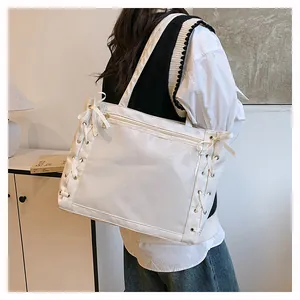 Close-up of white glossy tote bag with ribbon tie details and front zipper pocket