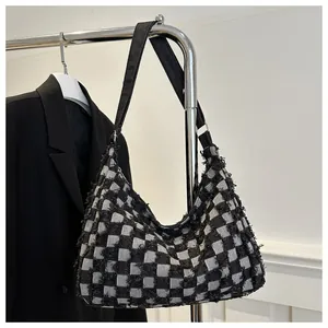 Detail of checkered tote bag with fringe texture and wide black shoulder strap