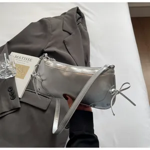 Chic silver mirror-finish baguette bag with side bows styled on a grey blazer set