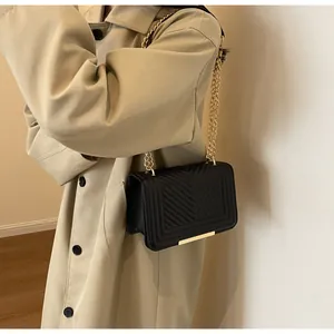 Close-up of elegant black V-quilted leather bag with golden chain strap on a model