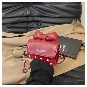 Detail van rode mini-tas met stippen met een grote strik en metallic fashion-tekst