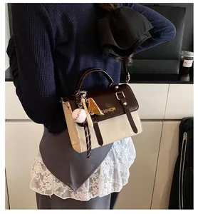 Detail of British style square bag with contrast strap and baseball theme pendant
