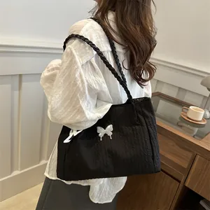 Large black pleated tote bag with white butterfly charm and woven shoulder straps