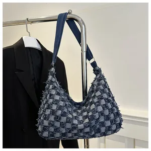 Detailed macro view of checkered denim fabric and fringe edges on the stylish shoulder bag
