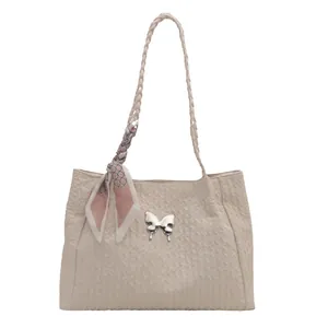 Quilted beige tote bag with a silver butterfly buckle and decorative pink silk scarf