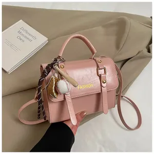 Vista detallada del bolso rosa con texto fashion y accesorios de dijes de béisbol