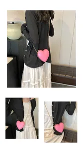 Détail d'un sac cœur rose vif avec cadre en métal doré et bandoulière en chaîne
