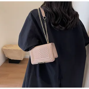 Detail of pink quilted square bag with gold chain strap and elegant chevron pattern